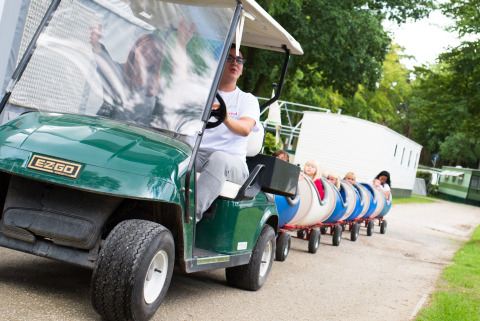 Bambini viaggiano su un piccolo trenino trainato da un golf cart al Camping Het Veen ad Anversa, Belgio.
