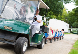 Bambini viaggiano su un piccolo trenino trainato da un golf cart al Camping Het Veen ad Anversa, Belgio.