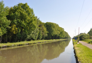 Rustig kanaal met groene bomen en pad bij Camping Het Veen, Antwerpen, België op een zonnige dag.
