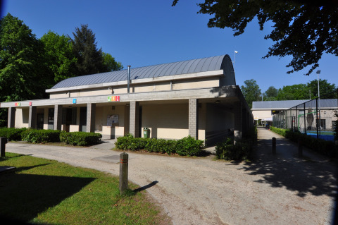 Main building at Camping Het Veen holiday park in Antwerp, Belgium, with greenery and clear blue sky.