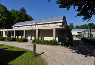 Main building at Camping Het Veen holiday park in Antwerp, Belgium, with greenery and clear blue sky.