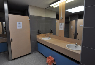 Bagno pubblico con lavandini, specchi e cabine al Camping Het Veen, parco vacanze ad Anversa, Belgio.