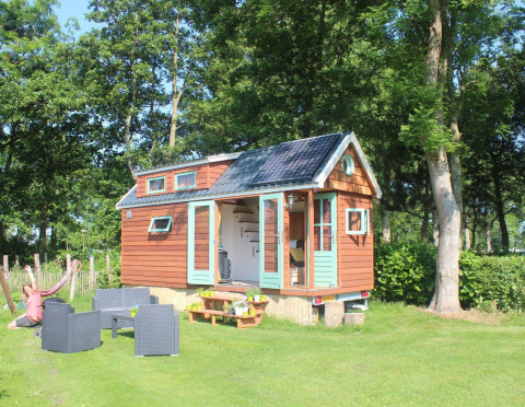 Klein houten tiny house met zonnepaneel en zitje bij Buytenplaets Suydersee in Nederland.