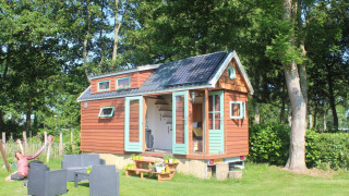 Tiny wood house with solar panels and outdoor seating at Buytenplaets Suydersee, Netherlands.