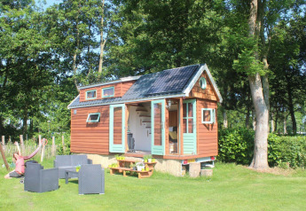 Lille træhus med solpanel, udendørs siddeområde og hængekøje ved Buytenplaets Suydersee i Nederlandene.