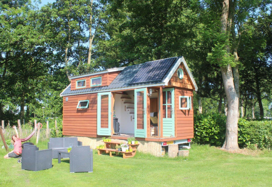 Pequeña casa de madera con paneles solares y zona exterior en Buytenplaets Suydersee, Países Bajos.