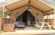 Tienda safari en Lac du Causse, Francia, con terraza de madera, asientos y mesa de picnic al aire libre.
