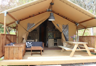 Tienda safari en Lac du Causse, Francia, con terraza de madera, asientos y mesa de picnic al aire libre.