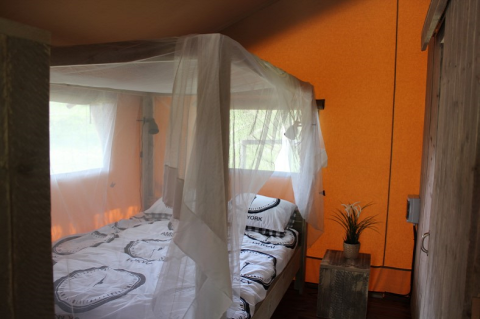 Dormitorio con mosquitera sobre la cama en safari tent en Lac du Causse, Francia.