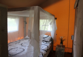 Dormitorio con mosquitera sobre la cama en safari tent en Lac du Causse, Francia.