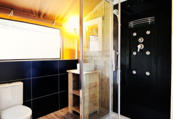 Moderne badkamer in safaritent bij Lac du Causse, Frankrijk, met douche, toilet en houten vloer.