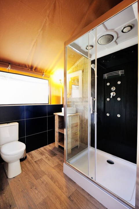 Modernes Badezimmer im Safarizelt am Lac du Causse, Frankreich, mit Dusche, WC und Holzboden.