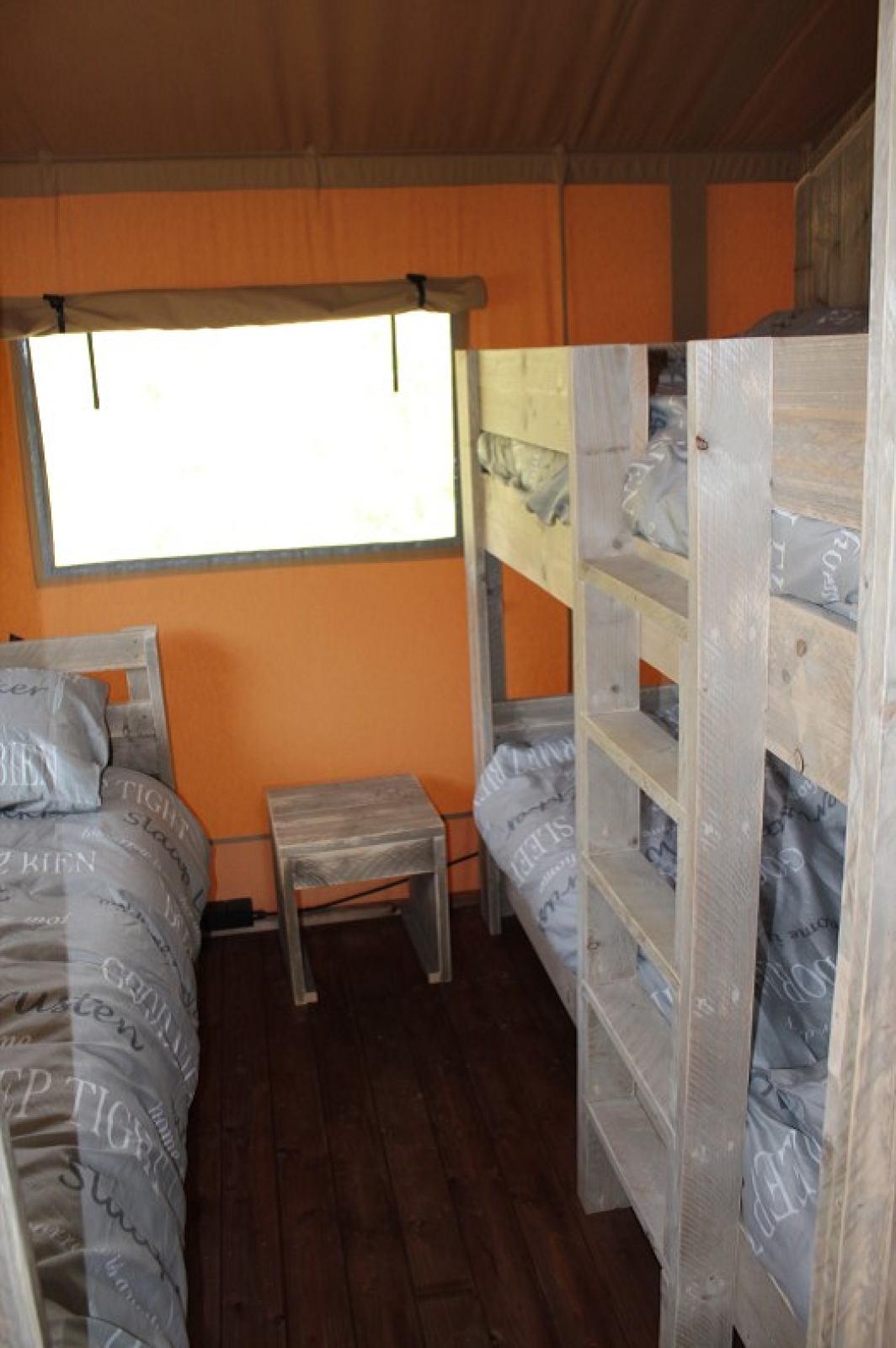 Interieur van slaapgedeelte met stapelbedden en houten meubilair in een safari-tent bij Lac du Causse, Frankrijk.