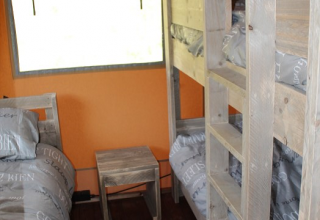 Interior view of sleeping area with bunk beds and wooden furniture in a safari tent at Lac du Causse, France.