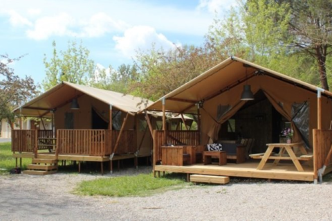 Zwei Safarizelte mit Holzterrasse am Lac du Causse in Frankreich, umgeben von Bäumen und Natur.