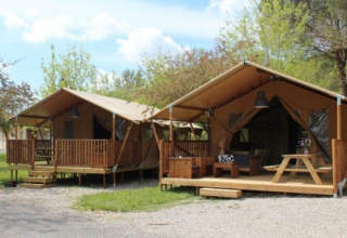 Two safari tents with wooden decks at Lac du Causse, France, surrounded by greenery and clear skies.