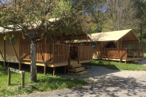 Safari-Zelte mit Holzveranda am Lac du Causse in Frankreich, umgeben von Bäumen und Natur.
