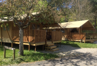 Tentes safari avec terrasses en bois au Lac du Causse en France, entourées d’arbres et de verdure.