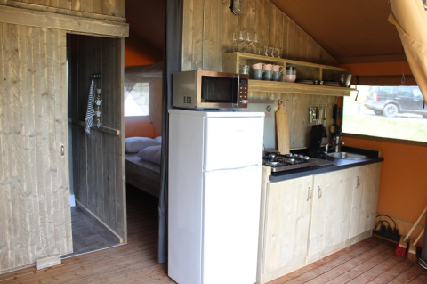 Innenansicht einer Safarizeltküche und Schlafzimmer am Lac du Causse, Frankreich, mit Holzmöbeln.