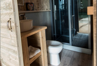 Badkamer in een safaritent bij Lac du Causse, Frankrijk, met houten meubels, wasbak, toilet en douche.