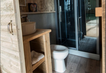 Baño dentro de una tienda safari en Lac du Causse, Francia, con decoración de madera y ducha moderna.