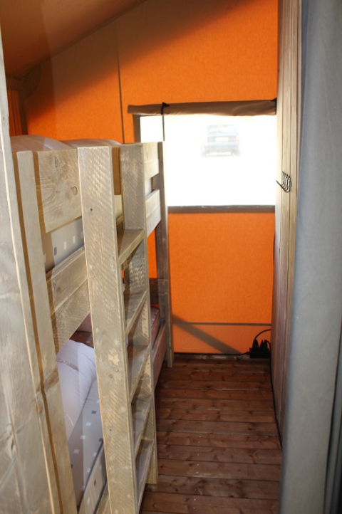 Interieur van een safaritent bij Lac du Causse in Frankrijk, met stapelbedden en houten vloer.