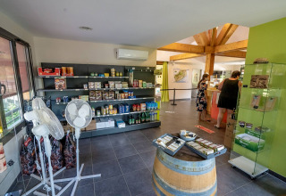 Shop interior at Lac du Causse holiday park in Nouvelle-Aquitaine, France, with shelves and visitors.