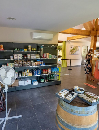 Interior de tienda en Lac du Causse, parque vacacional en Nouvelle-Aquitaine, Francia, con estantes y clientes.