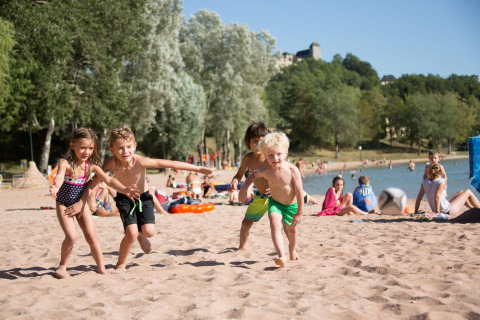Des enfants jouent sur la plage de sable du Lac du Causse, parc de vacances en Nouvelle-Aquitaine, France, au soleil.