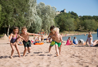 Bambini che giocano sulla spiaggia sabbiosa del Lac du Causse, parco vacanze in Nouvelle-Aquitaine, Francia, al sole.