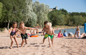 Children playing on the sandy beach of Lac du Causse holiday park in Nouvelle-Aquitaine, France, on a sunny day.