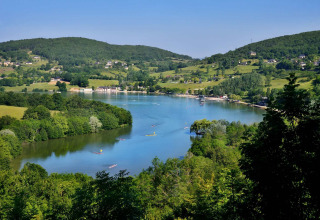 Scenic view of Lac du Causse holiday park in Nouvelle-Aquitaine, France, with green hills and calm waters.