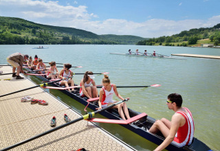 Squadra di canottaggio si prepara sulla riva del Lac du Causse, parco vacanze in Nouvelle-Aquitaine, Francia.