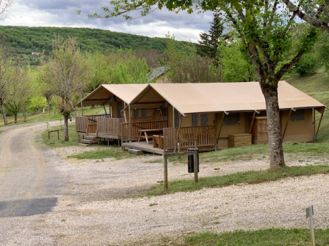 Safaritenten met houten veranda’s in Lac du Causse vakantiepark, Nouvelle-Aquitaine, Frankrijk, omringd door groen.