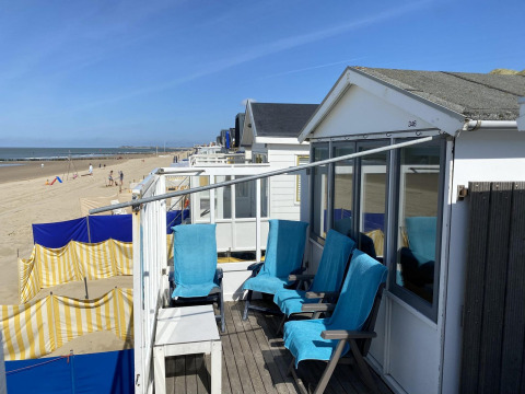 Casa de playa con sillas azules frente a la playa de arena y el mar en Dishoek, Zeeland, Países Bajos.