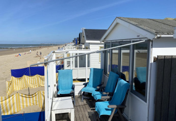 Strandhaus mit blauen Stühlen, Blick auf Sandstrand und Meer in Dishoek, Zeeland, Niederlande.
