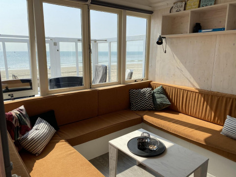 Sala luminosa en Beach house 'Dishoek 345/346', con grandes ventanas al mar y la playa en Zeeland, Países Bajos.