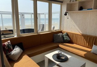 Bright lounge in Beach house 'Dishoek 345/346' with windows overlooking the beach and sea in Zeeland, Netherlands.