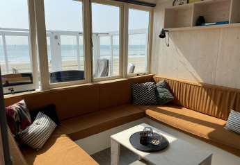 Bright lounge in Beach house 'Dishoek 345/346' with windows overlooking the beach and sea in Zeeland, Netherlands.