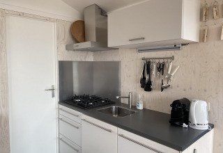 Cocina moderna de cabaña con estufa de gas, fregadero, cafetera y hervidor en Beach house 'Dishoek 345/346', Zeeland.