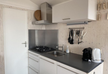 Cocina moderna de cabaña con estufa de gas, fregadero, cafetera y hervidor en Beach house 'Dishoek 345/346', Zeeland.