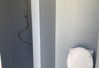 A cabin bathroom with a shower on the left and a toilet on the right, both in a minimalistic design.