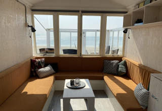 Strandhusets hyggelige opholdsstue med store vinduer, havudsigt og moderne siddepladser i Dishoek.