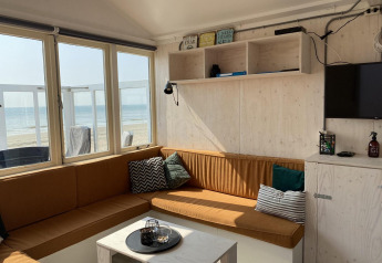 Soggiorno luminoso in casa sulla spiaggia con vista mare, angolo relax e arredi moderni a Zeeland, Olanda.