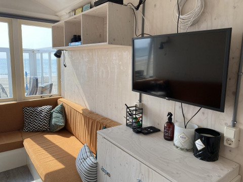 Área de estar soleada en Beach house 'Dishoek 345/346' con televisor, vista al mar y decoración cómoda.