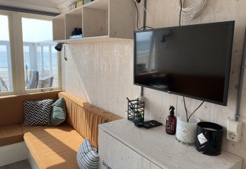 Área de estar soleada en Beach house 'Dishoek 345/346' con televisor, vista al mar y decoración cómoda.