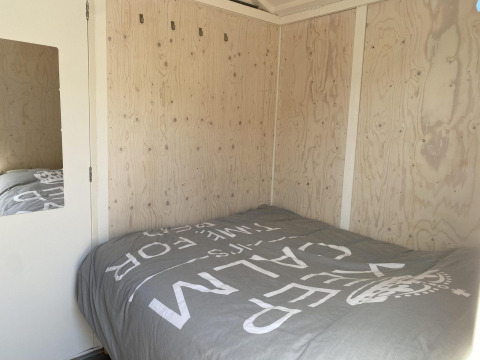 Bedroom in a wooden cabin with a double bed and gray bedding at Beach house 'Dishoek 345/346'.