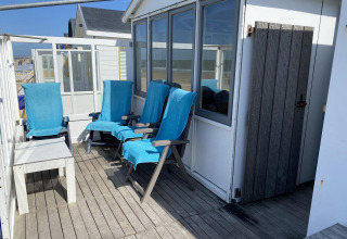Terraza de la casa de playa Dishoek 345/346 con sillas azules en Welcome.in - Zeeland, Países Bajos.