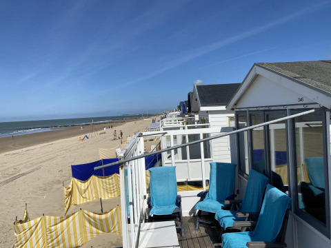 Strandhuisjes met blauwe stoelen en gele windschermen op het zand van Dishoek, Zeeland, Nederland.