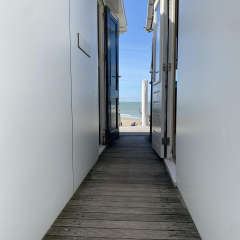 Vue depuis une cabane de plage à Dishoek, Zélande, Pays-Bas, avec portes ouvertes donnant sur la mer.